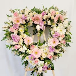 Heart-shaped floral wreath with pink and white flowers on an easel
