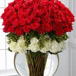 Large arrangement of red roses over white blooms in a round clear glass vase