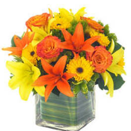 Orange and yellow flowers arranged in a clear square vase