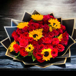 Bouquet of red roses and yellow sunflowers wrapped in black paper