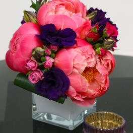 Pink and purple floral arrangement in a clear square vase