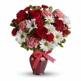 Bouquet of red roses, pink carnations, and white daisies in a red vase