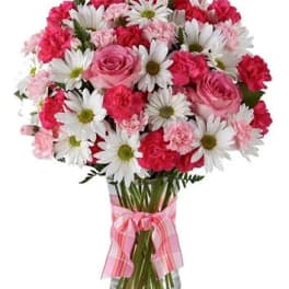Pink and white bouquet of roses, carnations, and daisies in a glass vase