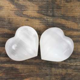 Two white heart-shaped stones on a wooden surface