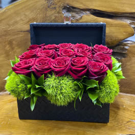Black woven box filled with red roses and bright green moss