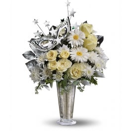 White and cream roses, gerberas, and mums in a tall silver vase with a silver masquerade mask pick.