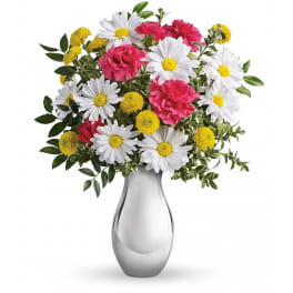 White daisies, yellow button poms, and pink carnations in a shiny silver vase