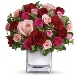 Bouquet of red, pink, and blush roses in a clear glass vase