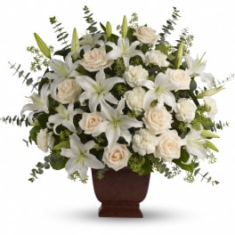 White lilies, roses, and carnations arranged in a brown pedestal vase