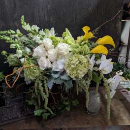 Large floral arrangement with white roses, green hydrangeas, and yellow calla lilies
