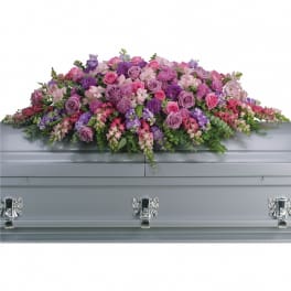 Full casket spray of pink and purple flowers on a gray casket