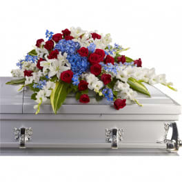 Red, white, and blue casket spray with roses, lilies, and hydrangea on a silver casket