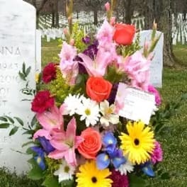 Colorful funeral flower arrangement placed beside a gravestone