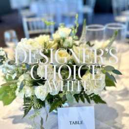 White rose centerpiece in a glass vase on an event table with a table card in front