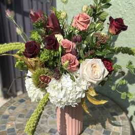 Tall bouquet of roses and white hydrangeas in a pink vase