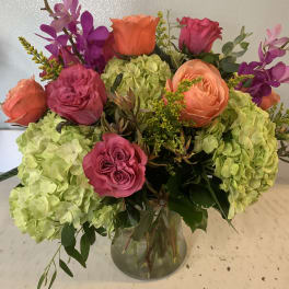 Bouquet of pink and orange roses with green hydrangeas in a glass vase