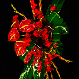 Red roses and tropical flowers with glossy green leaves on a black background