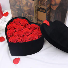 Red roses in a black heart-shaped box with the lid beside it