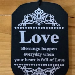 Black hanging plaque with the word Love and decorative white scrollwork