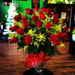 Large bouquet of red roses in a glass vase with a red ribbon