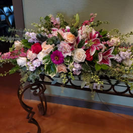 Large mixed floral arrangement with pink lilies and roses on a table