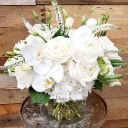 White roses and orchids arranged in a clear glass vase