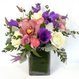 Bouquet of purple, pink, and white flowers in a square glass vase