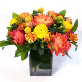 Orange and yellow mixed bouquet in a square glass vase