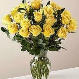Large bouquet of yellow roses arranged in a clear glass vase