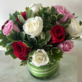 Bouquet of red, white, and pink roses in a striped glass vase