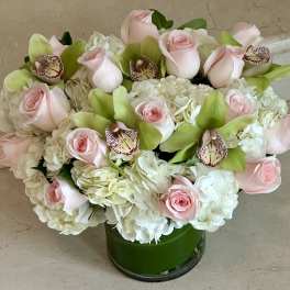 Pink roses and white hydrangeas with green orchids in a glass vase