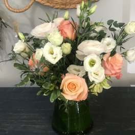 Mixed bouquet of peach and white flowers in a dark glass vase