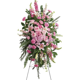 Tall pink floral standing spray on an easel with lilies, roses, and carnations