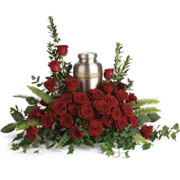 Red roses arranged around a silver urn with greenery
