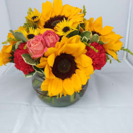 Sunflowers and pink roses arranged in a glass vase
