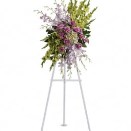 Standing floral spray with purple roses and green orchids on an easel