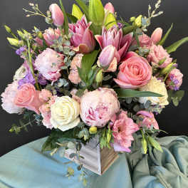 Pink and white bouquet with roses, tulips, and peonies in a square vase