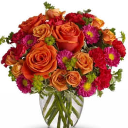 Orange roses and pink daisies in a clear glass vase