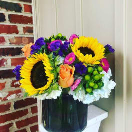 Bright mixed bouquet with sunflowers, roses, and daisies in a dark vase