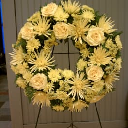 Standing wreath of pale yellow roses and mums on a metal easel