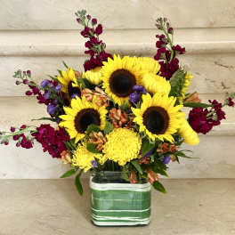 Sunflowers and mixed blooms arranged in a striped glass vase