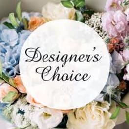 Pastel mixed flower arrangement with a circular label reading Designer's Choice.