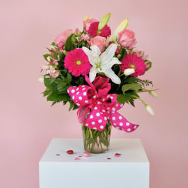 Pink and white bouquet in a glass vase with a polka-dot ribbon