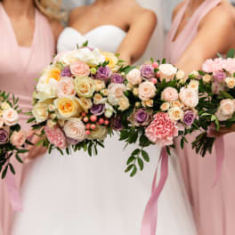 Bridesmaids holding pastel rose bouquets with pink dresses