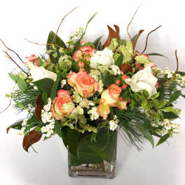 Peach and white roses in a square glass vase with mixed greenery