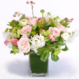Pink roses and white blooms arranged in a square glass vase