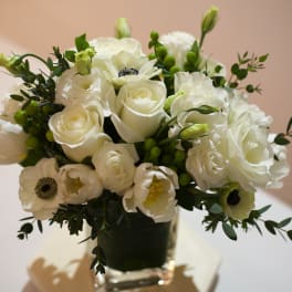 White roses and anemones arranged in a clear glass vase
