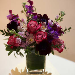 Mixed bouquet of pink, purple, and white flowers in a clear glass vase