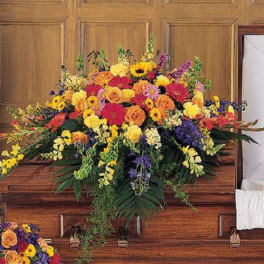 Large colorful flower spray on a wooden casket
