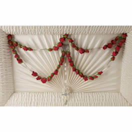Red rose garland draped over a white satin-lined casket with a rosary and cross